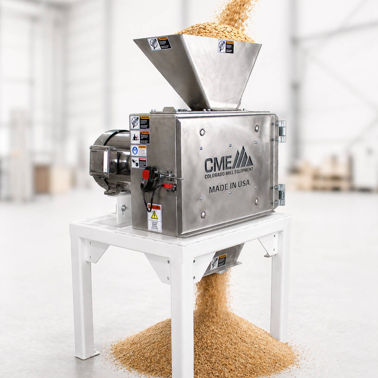 Wheat grain being poured into the top of a hammer mill to be ground into particles used for pellets